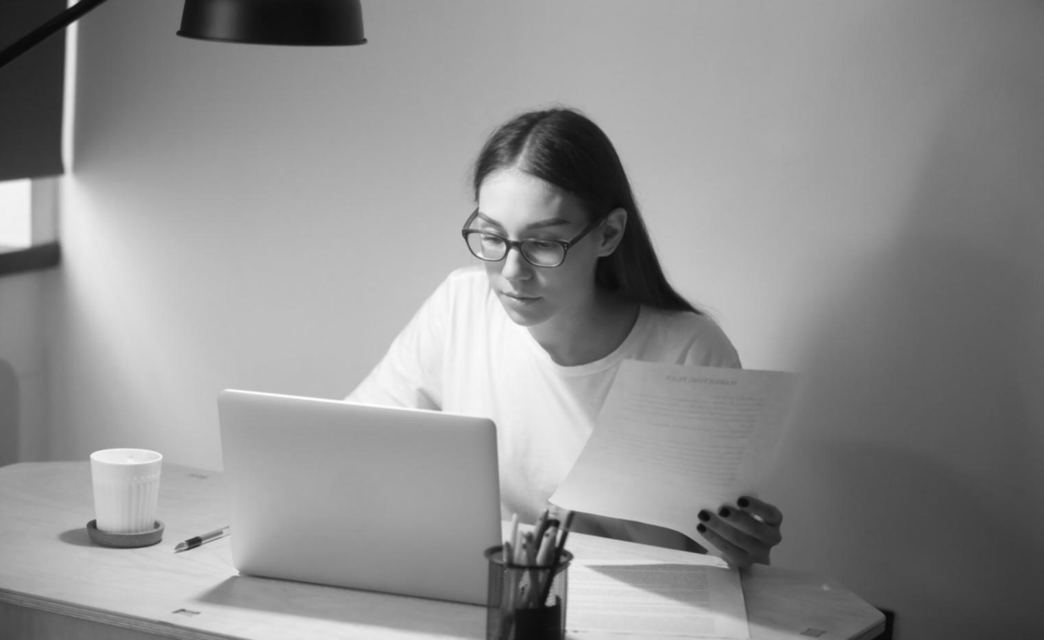 Persona analizando gráficos financieros estacionales en ordenador con calculadora y documentos sobre mesa de trabajo